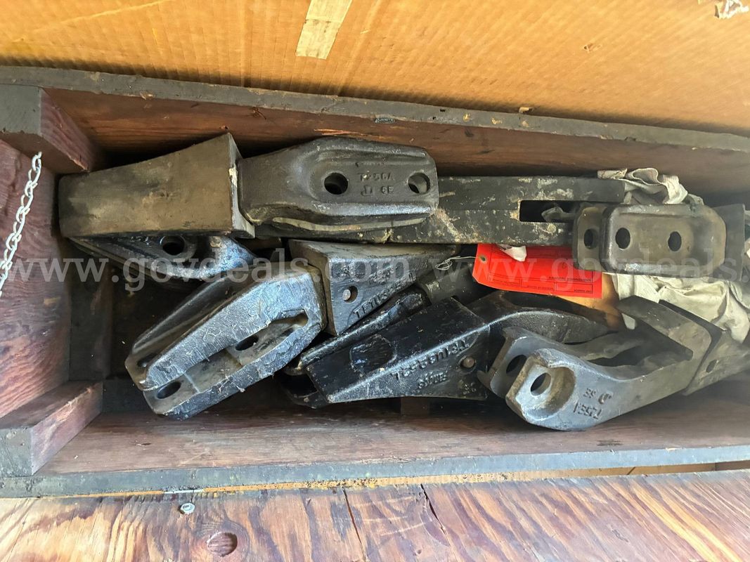 Heavy box of bolt-on shanks and cutting teeth for digging buckets.