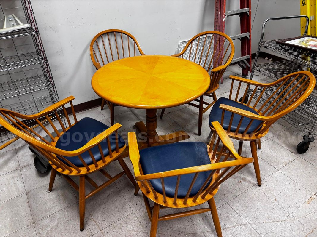 Used wooden dining table set with matching chairs and blue seat cushions.