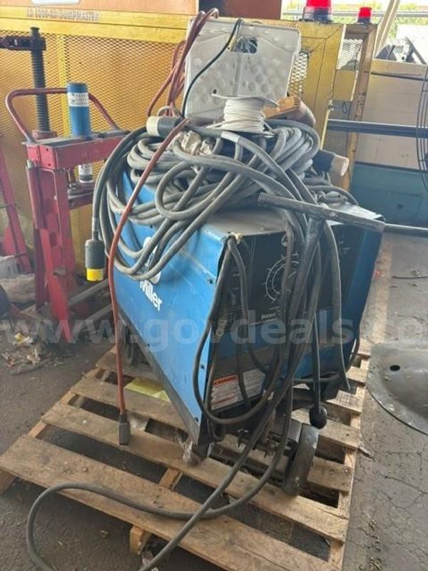 Miller Millermatic 252 MIG Welder sitting on a wooden pallet with coiled cables and a wire spool on top
