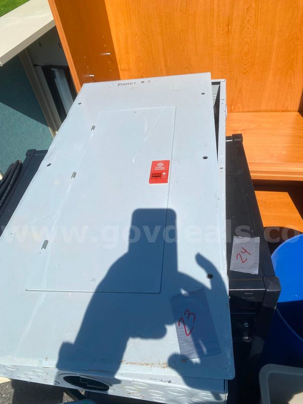 Electric panel with breakers, metal desk (1), metal bookshelf (1), metal hutch with light
